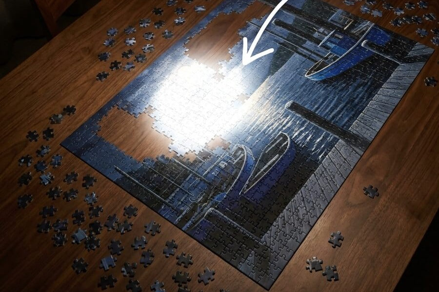A close view of a glossy unfinished puzzle section with a bright glare patch hiding piece detail
